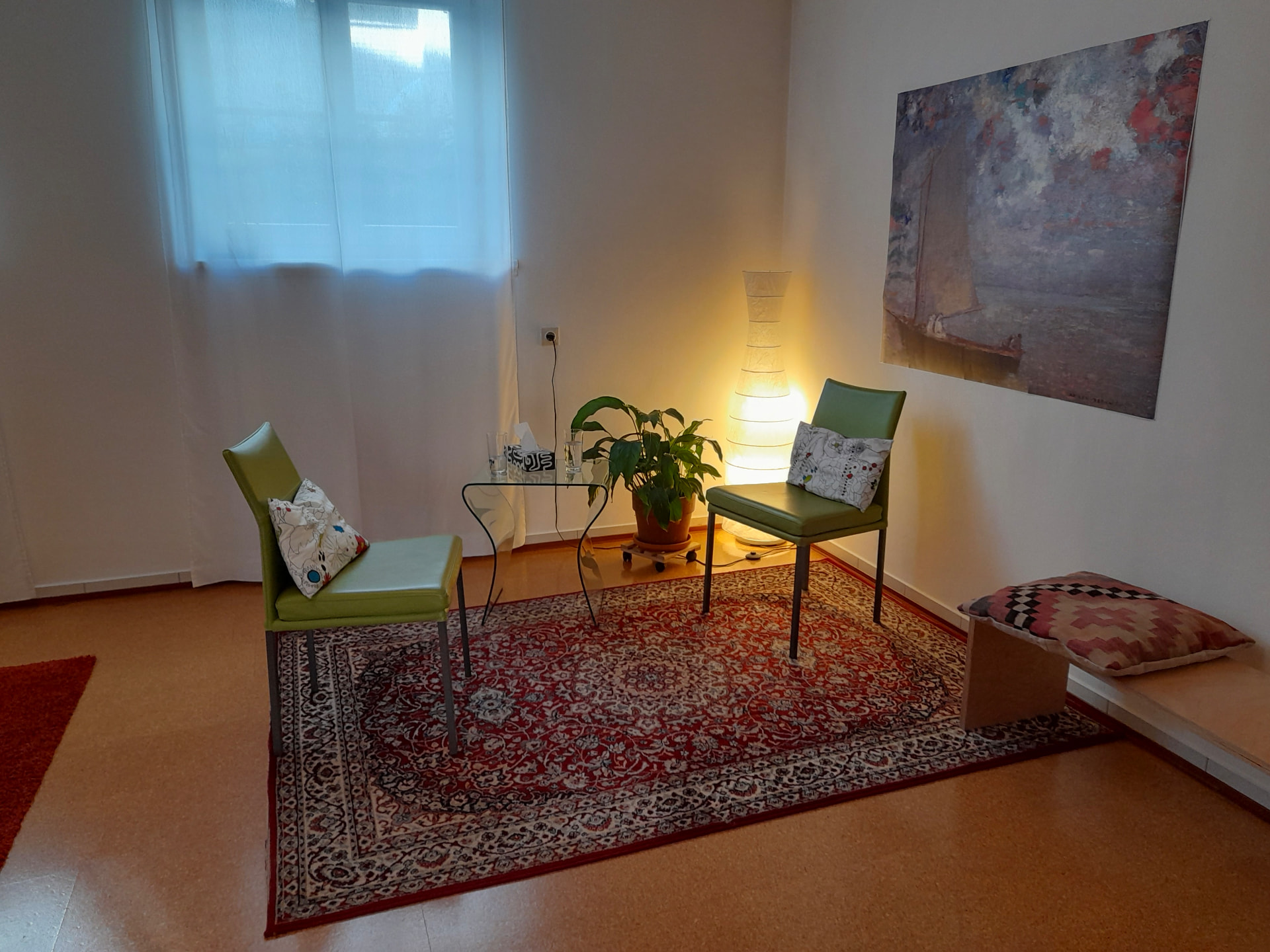 Praxisraum mit zwei grünen Sesseln, Orientteppich, Pflanze und Segelboot-Bild an der Wand
