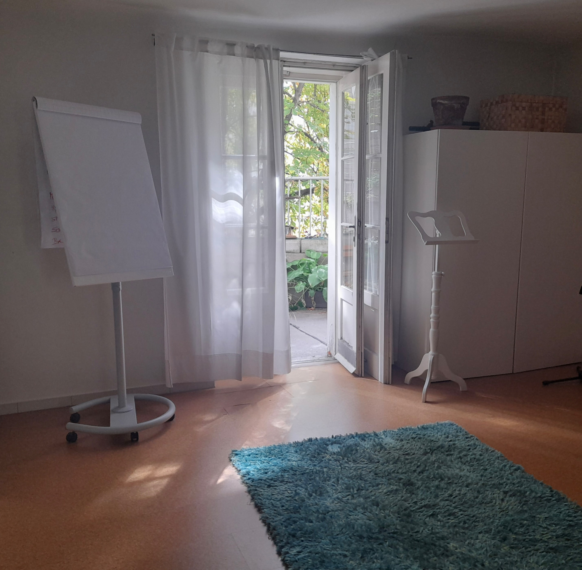 Praxisraum mit offenem Fenster, Flipchart und blauem Teppich